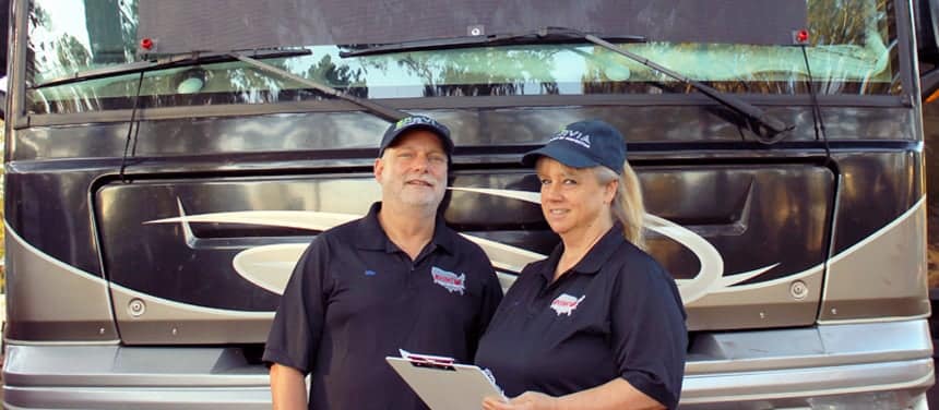 Two people standing in front of an RV undergoing inspection for RV inspection services.