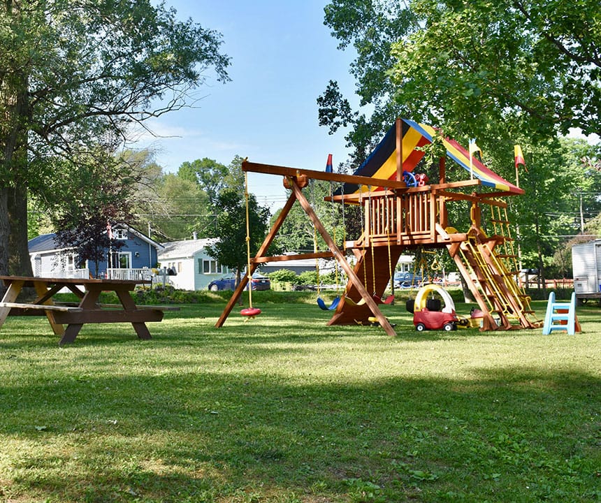 A NY Campground playground with a swing set and picnic table, perfect for seasonal stays.