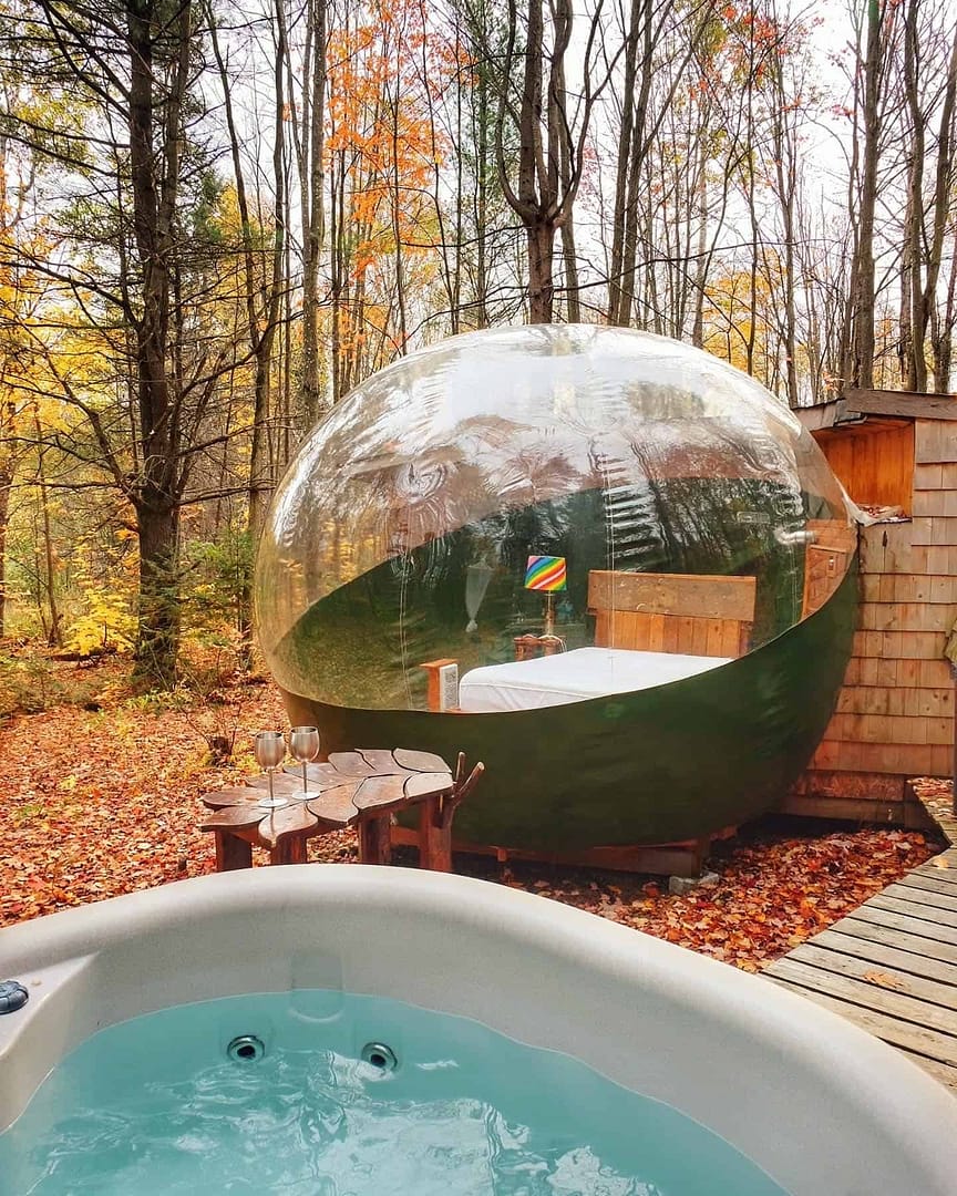 A glamping experience in a bubble tent nestled in the woods with a luxurious hot tub.