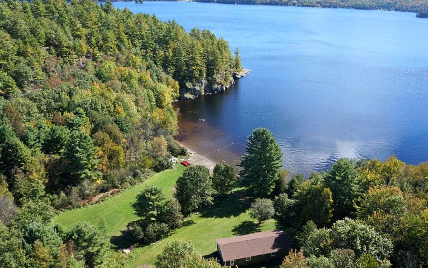 Pitman's Bay Campground offers overnight camping options with stunning aerial views of a lake surrounded by trees.