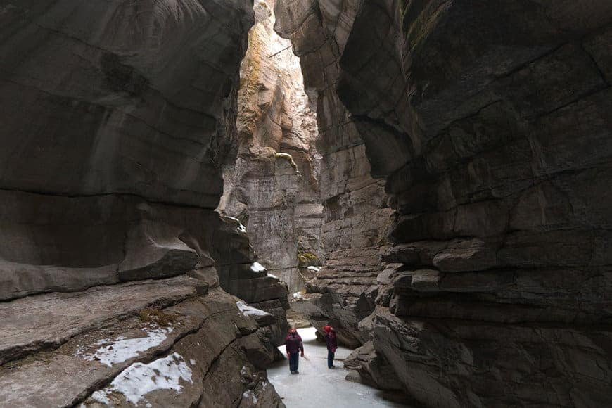 Two people walking through a narrow canyon in Jasper National Park.