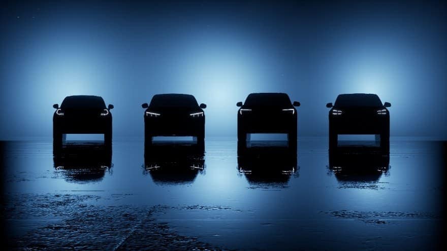 Four bold, all-electric Ford SUVs are lined up in a dark room.