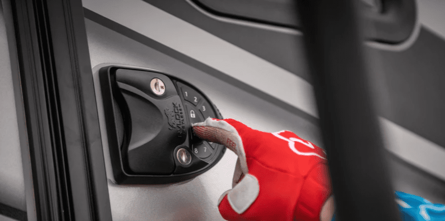 A person is holding a door handle on an RV, considering a keyless upgrade with RVLock for motorhomes.