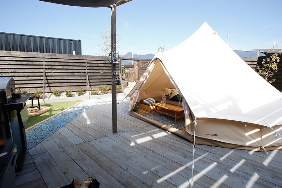 A luxurious white tent sits on a wooden deck with Mt. Fuji in the background, creating the perfect glamping site.