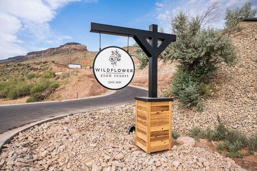 A wooden sign in front of a mountain at Zion Wildflower Resort.