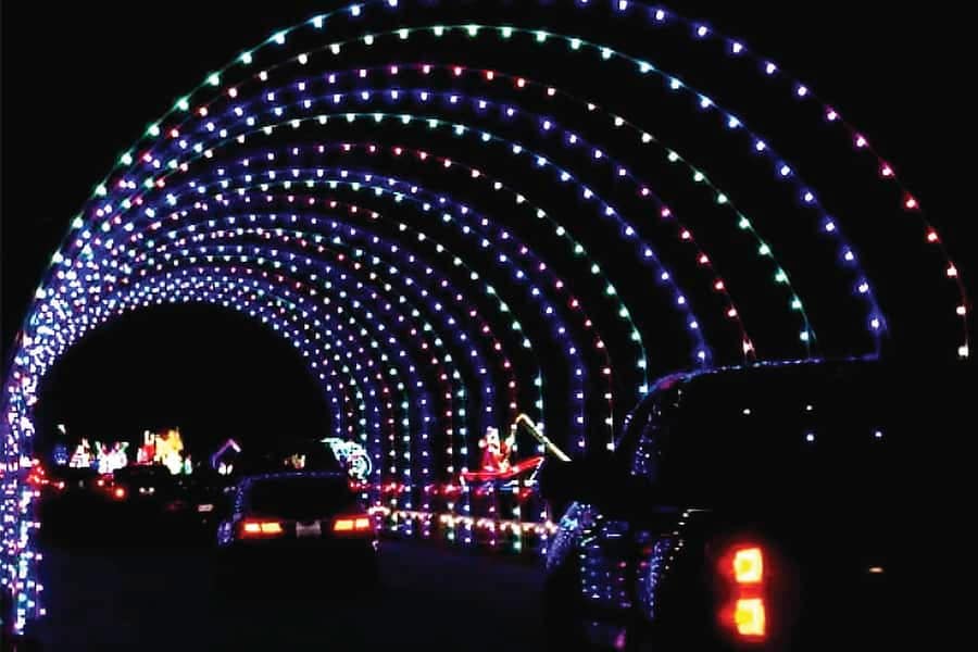 Wawaloam Campground hosts a mesmerizing Festival of Lights during the Holiday Season, featuring a captivating tunnel illuminated by an array of vibrant colors, with cars driving through it.