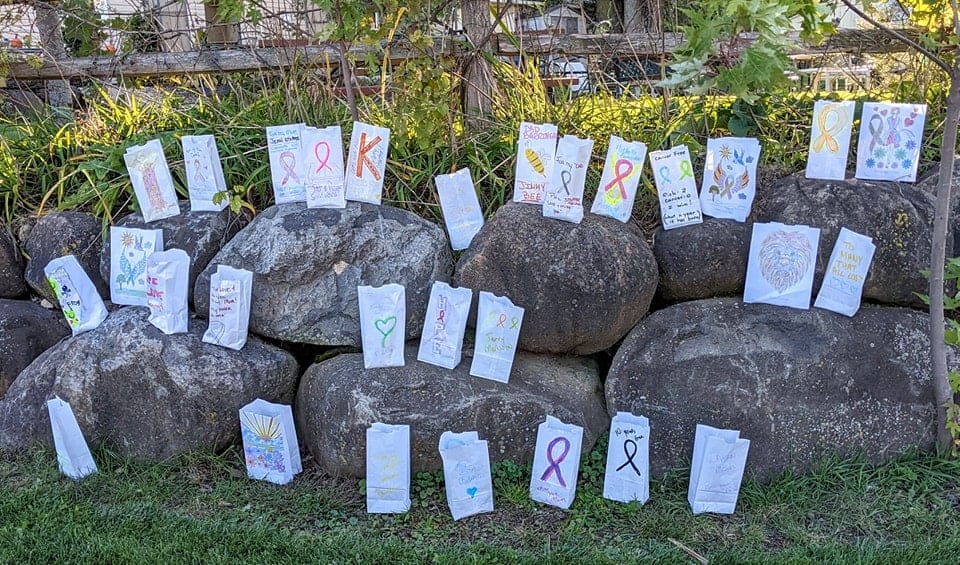Cancer survivors gather at private campgrounds in Glacier Valley Campground, placing paper bags on a group of rocks as a symbolic gesture.