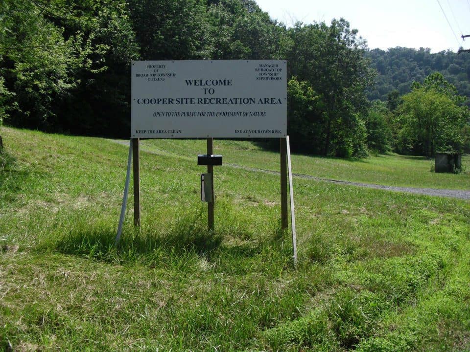 A Cooper's campground sign in the middle of a grassy field.