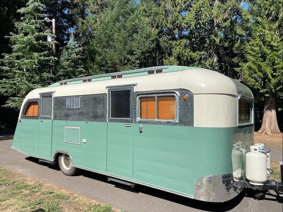 A vintage green and white camper trailer, a 1950 Westcraft Coronado, parked in a parking lot.