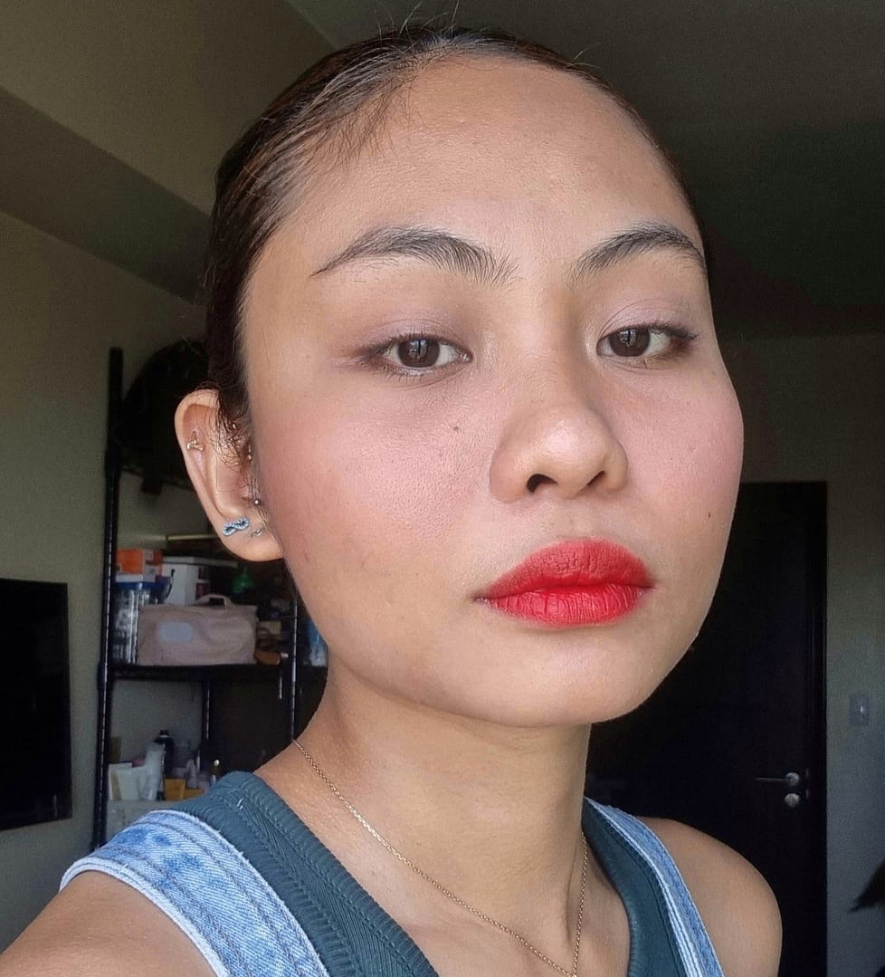Über uns: Eine Frau posiert mit einem roten Lippenstift, der gerade dabei ist, ihn auf ihre Lippen aufzutragen.