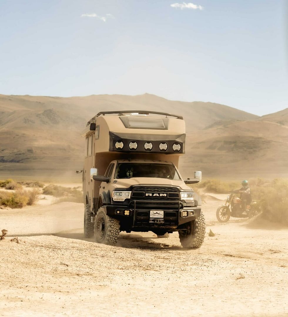 The HILT, a Class C Adventure Truck from Storyteller Overland, perches atop a truck driving through the desert.