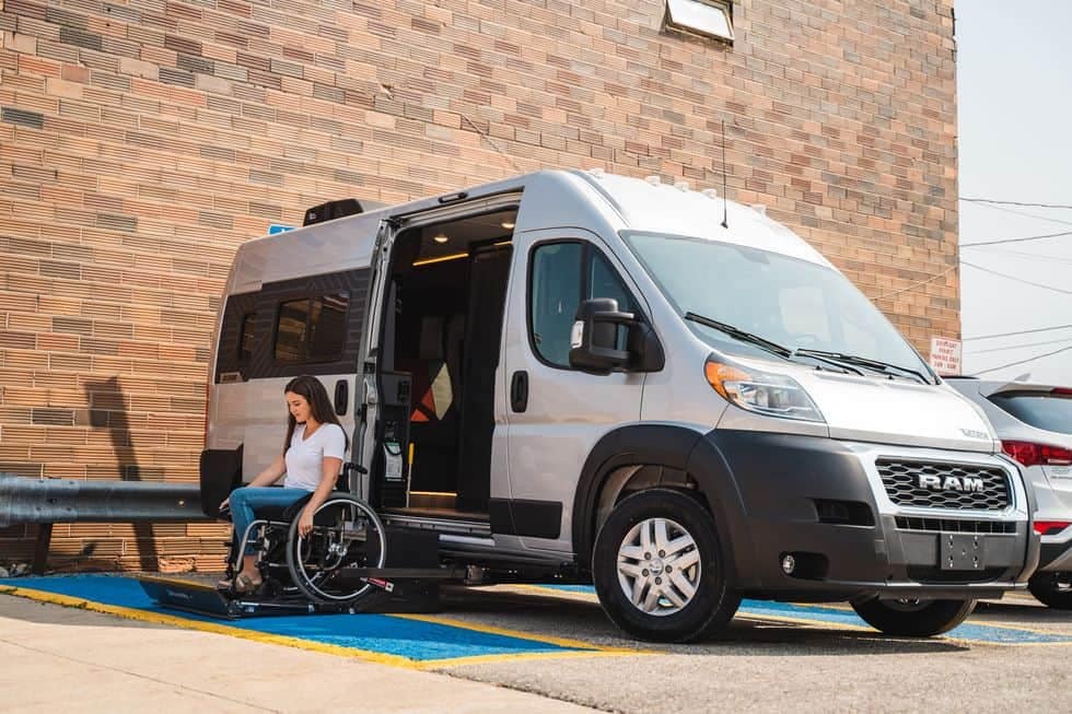 An accessible woman in a wheelchair in front of a Ram ProMaster van.