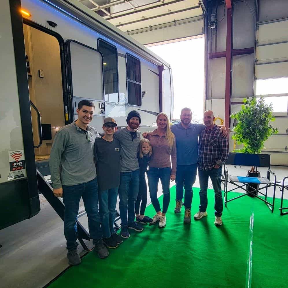 A group of people standing in front of an Intentional Adventure rv.