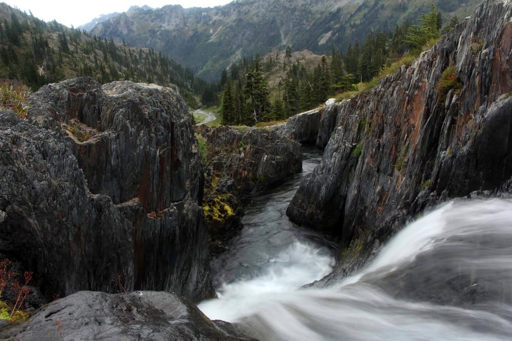A picturesque waterfall flows through a rocky canyon, undeterred by campground closures or winter storms at Hurricane Ridge.