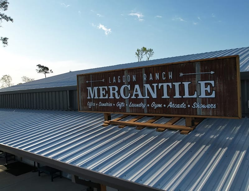 A large metal sign reading "Lagoon Ranch Mercantile" with listed amenities is mounted on the roof of a metal building.