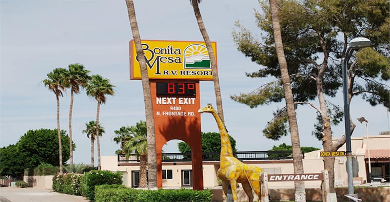 Sign for Bonita Mesa RV Resort displays temperature as 83°F; a giraffe statue and palm trees are visible near the entrance.